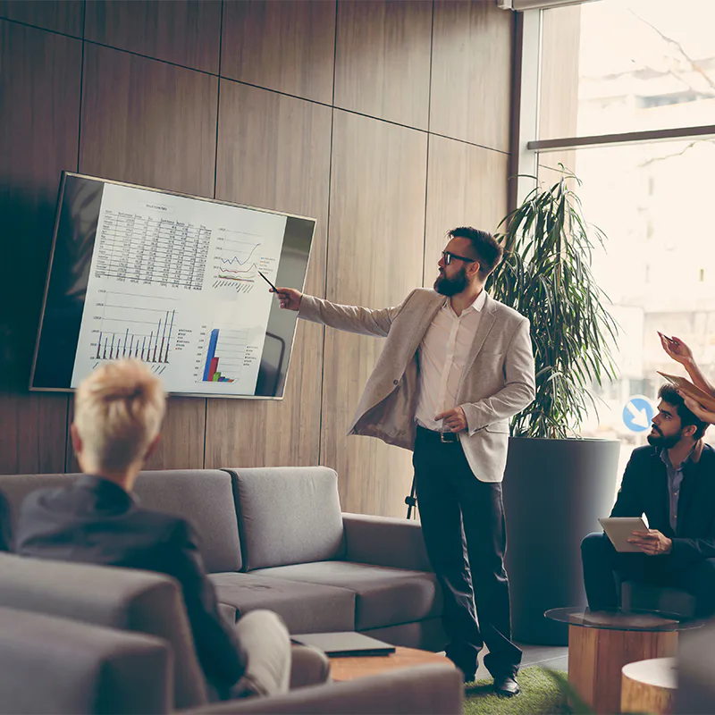 Presenter pointing to sales charts during a meeting