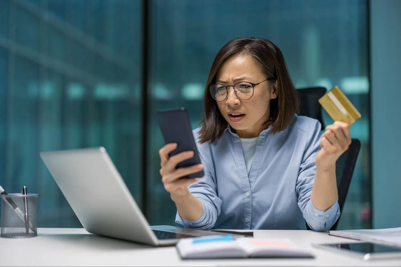 A shocked woman checks her bank account after falling for a scam