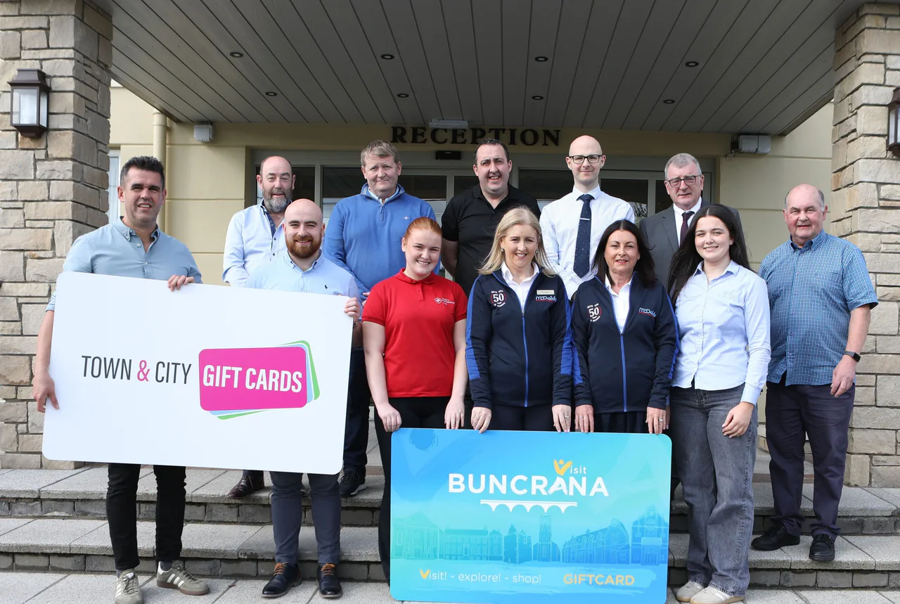 Buncrana business representatives holding Town & City Gift Cards and Visit Buncrana signs outside a building