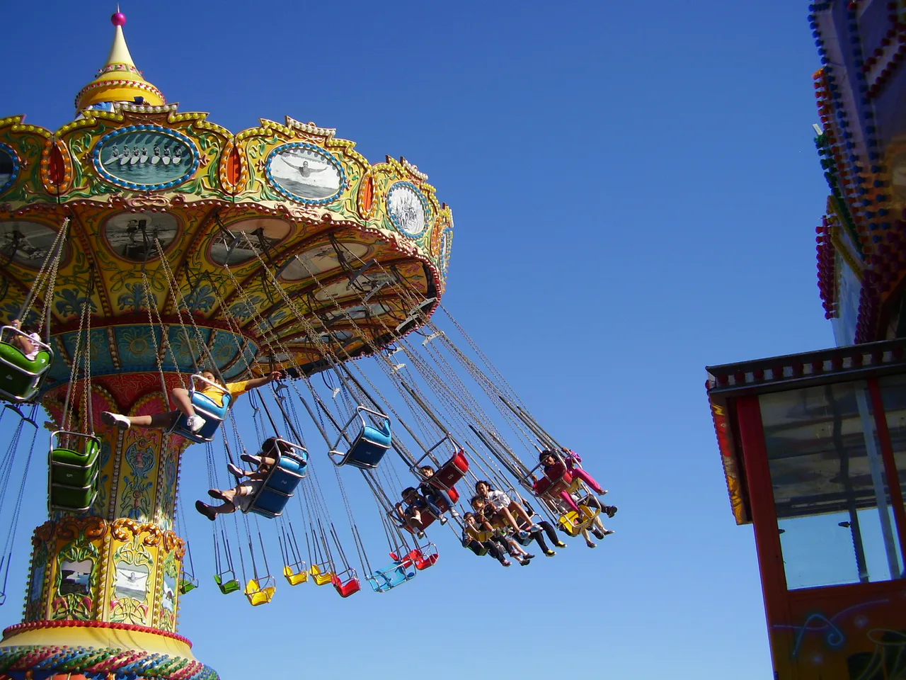 Visitors on a swing ride at the Santa Cruz Beach Boardwalk against a blue sky, photographed in July 2010.