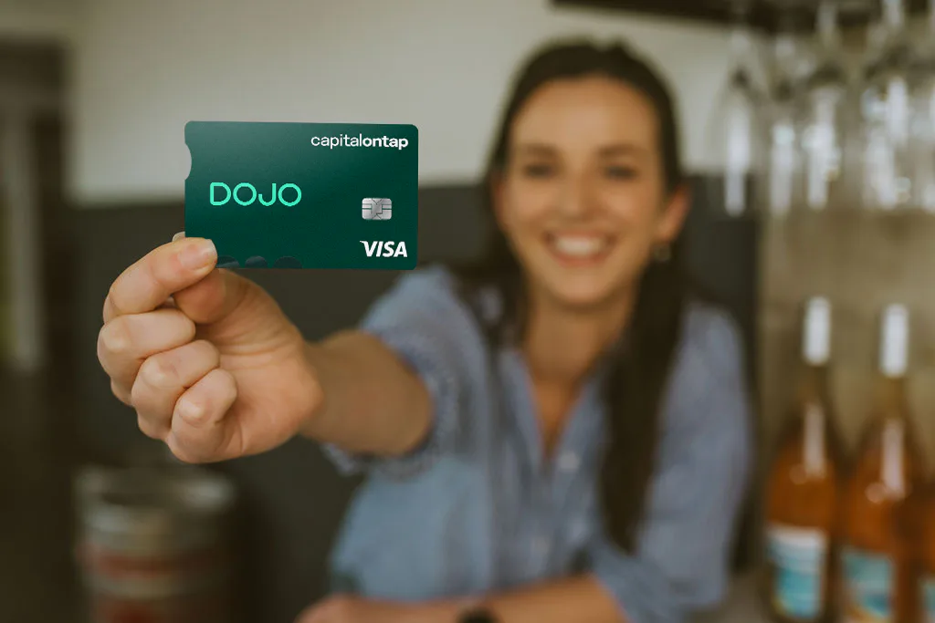 A business owner holding the Dojo and Capital on Tap card in a wine shop