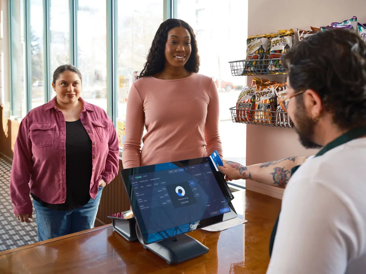 A customer hands a gift card to a restaurant cashier beside a payment terminal.