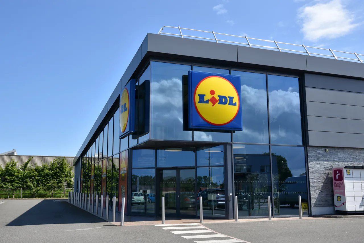 Glass-fronted Lidl supermarket in Saint-Aubin-sur-Scie, France, under a blue sky.