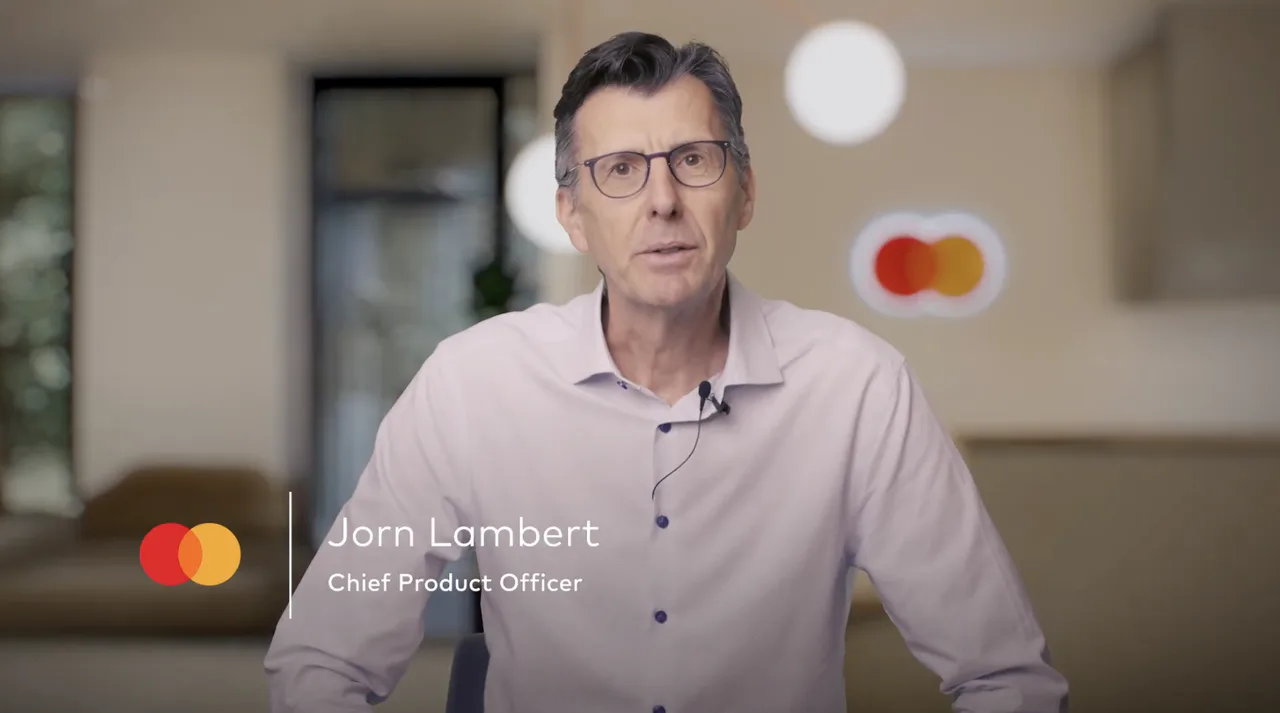 Mastercard video still showing its chief product officer speaking in an office.
