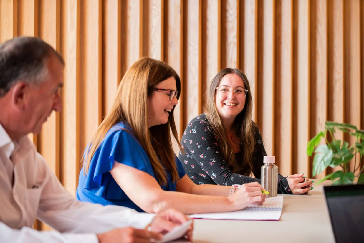 Three people talking around a meeting table in an archive photograph published by the Government Commercial Agency.