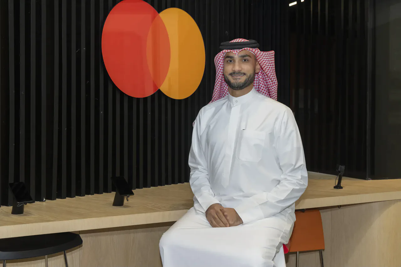 Mastercard executive seated beside the Mastercard logo.