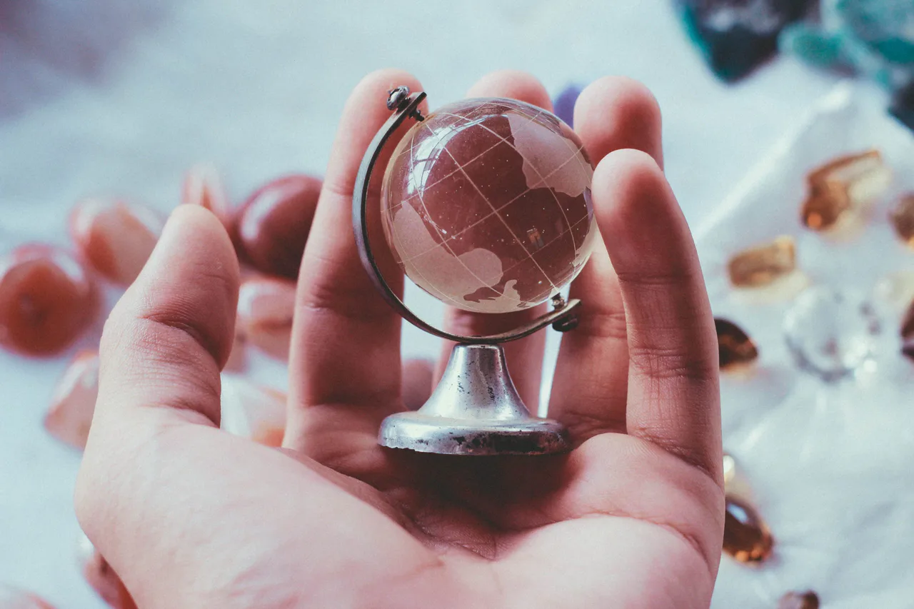 A small transparent globe held in a person’s hand